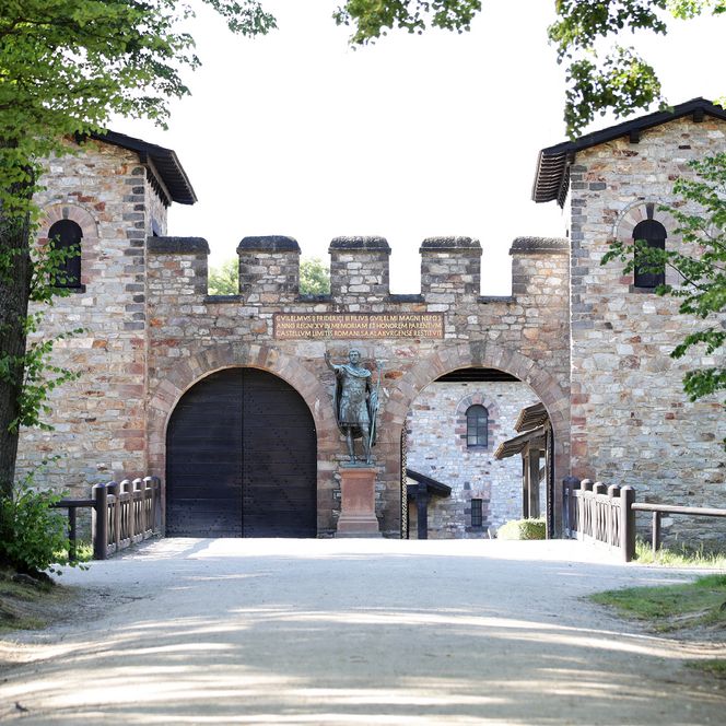 in ca. 20 Meter Entfernung vom Fotograf befindet sich das EIngangsportal zum Römerkastell Saalburg. Links und rechts sind kleinere Wachtürme, dazwischen zwei Rundbögen zum durchgehen, eines davon ist geöffnet. 