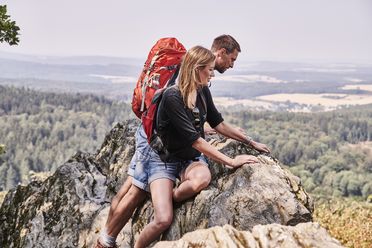 Zwei Wanderer sind auf den Großen Zacken geklettert und genießen die Aussicht. 