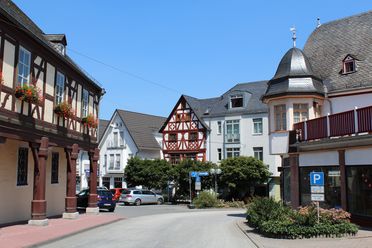 Blick in den Ortskern von Weilmünster. Es sind sowohl restaurierte Fachwerkhäuser, als auch modernere Häuser zu sehen. Das Foto wurde auf der Straße in der Mitte stehend aufgenommen. 