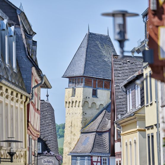 Blick durch eine Gasse in Bad Camberg. Zu sehen ist jeweils ungefähr die obere Hälfte der Häuser bei blauem Himmel