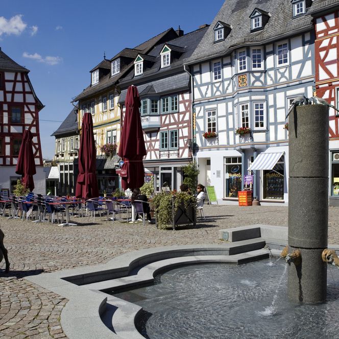 im Vordergrund der Brunnen am Marktplatz Bad Camberg, im Hintergrund mehrere Fachwerkhäuser