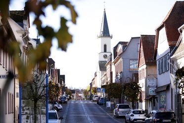 Blick entlang einer Straße in Friedrichsdorf. Auf der rechten Seite befindet sich die Evangelische Kirche