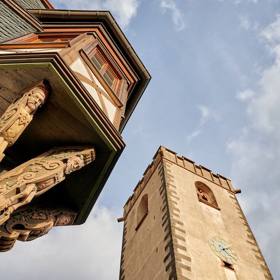Ein alter Turm und ein Fachwerkhaus unter blauem Himmel.