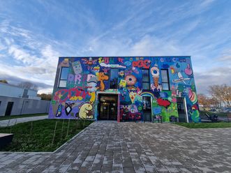 Das Foto zeigt die Fassade des Kinder- und Jugendhaus in Eschborn. Diese wurde bunt gestaltet, hauptsächlich mit Graffiti. 