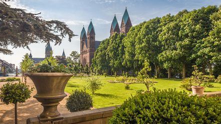 Im Vordergrund ist eine Parkanlage in Bad Homburg zu sehen, im Hintergrund hinter Bäumen sieht man die Erlöserkirche mit 4 Kirchtürmen. 